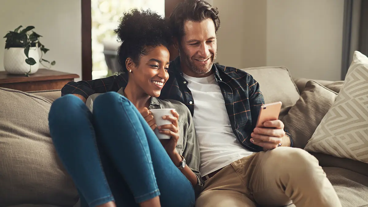 couple looking at mobile phone on couch