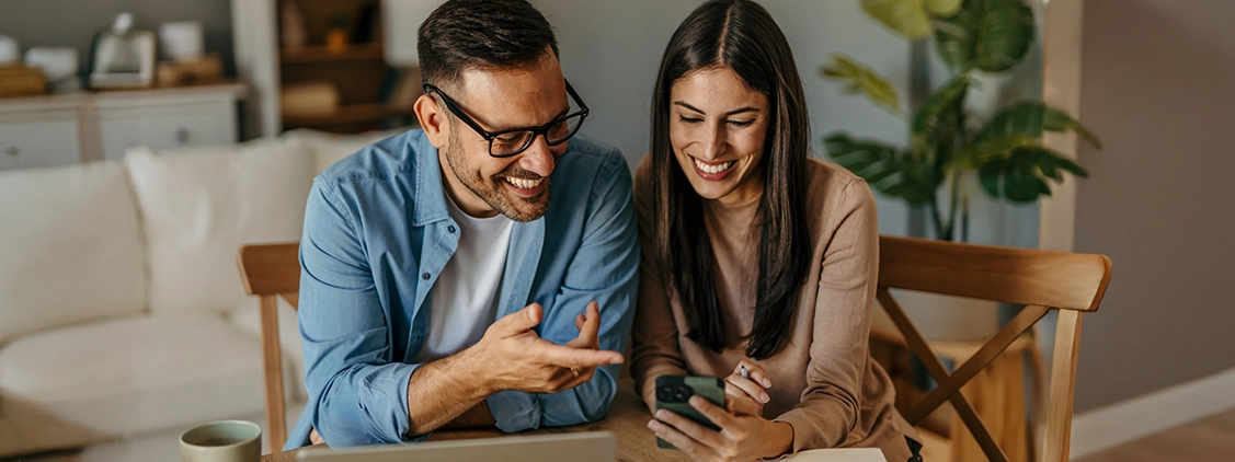 fpo-image happy couple sitting at a table looking at a mobile phone