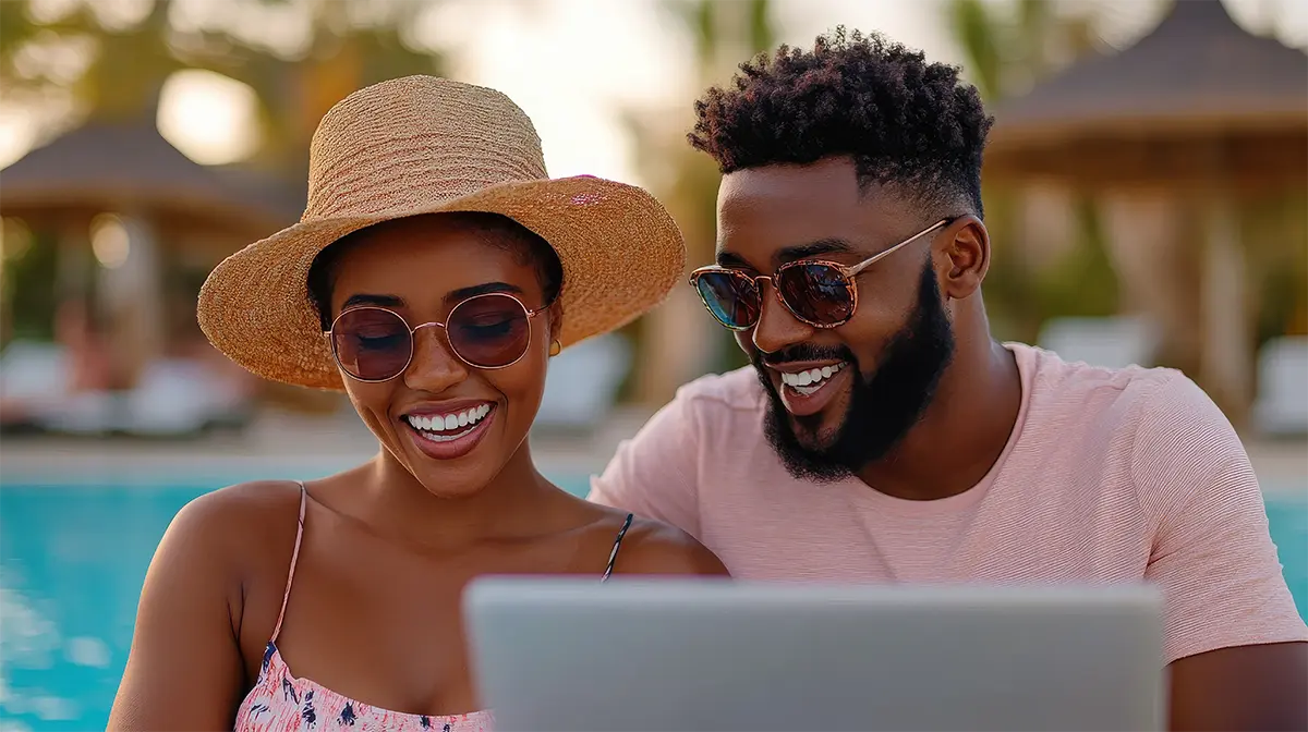 happy couple using laptop by pool on vacation