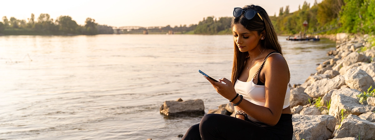 young woman using mobile phone on the bank of a river