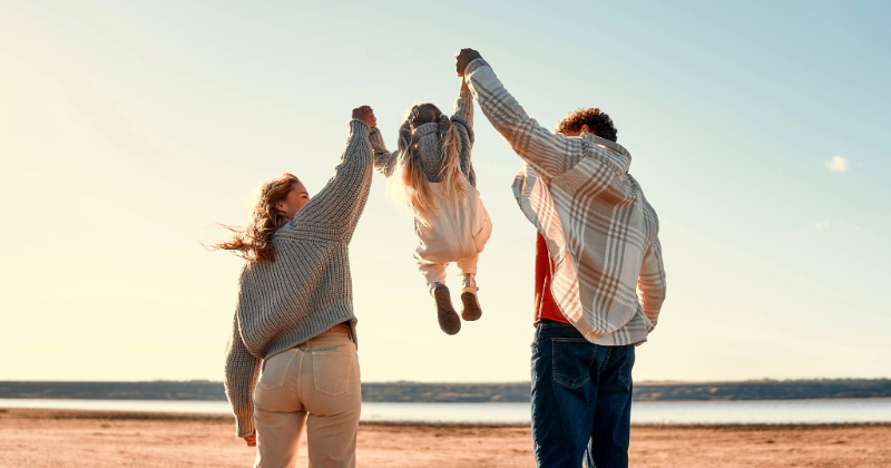 Happy young family with their little beloved daughter playing and having fun outside on their weekend