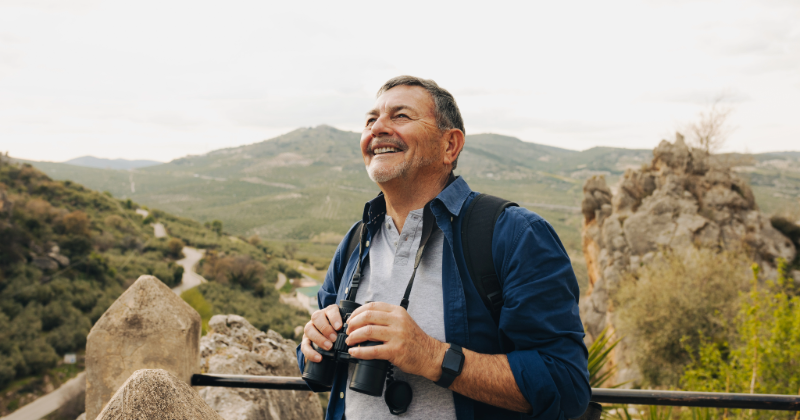 Happy senior man looking at the view from a hilltop