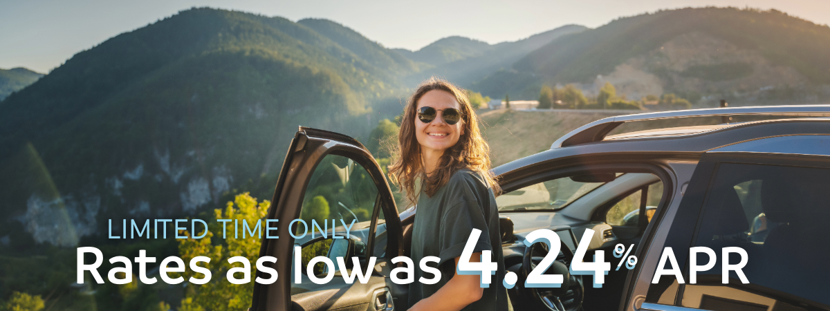 young girl getting out of her car in front of an overlook with mountains in the background