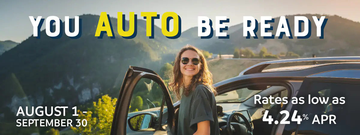young girl getting out of her car in front of an overlook with mountains in the background
